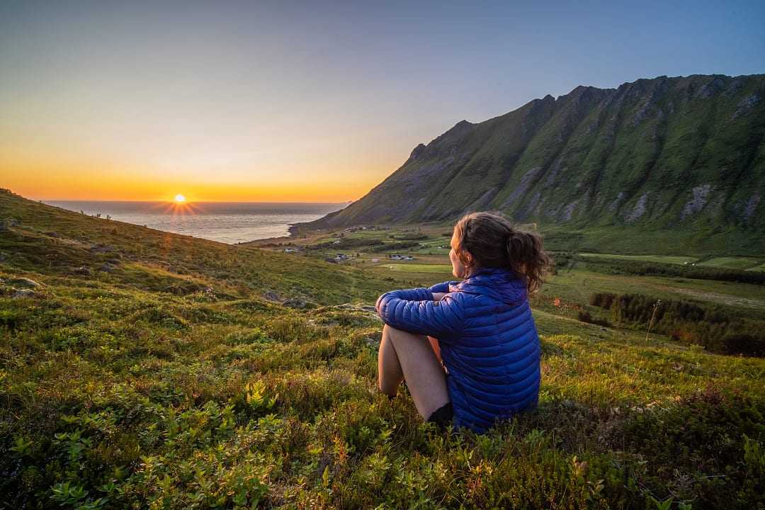 Hiker watching the midnight sun in Lofoten, Norway