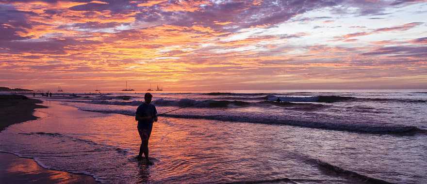 Fisherman silhouetted against the setting sun on Playa Tamarindo in Costa Rica