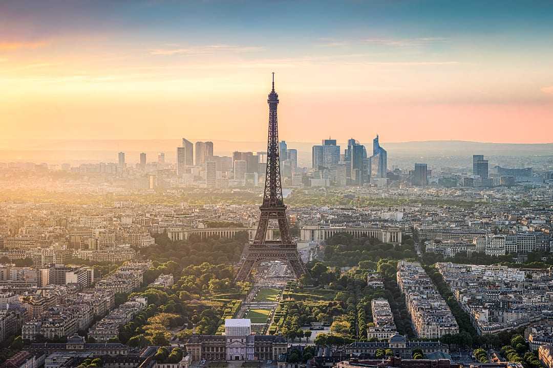 The Eiffel Tower stands tall over Paris with golden sunset hues.