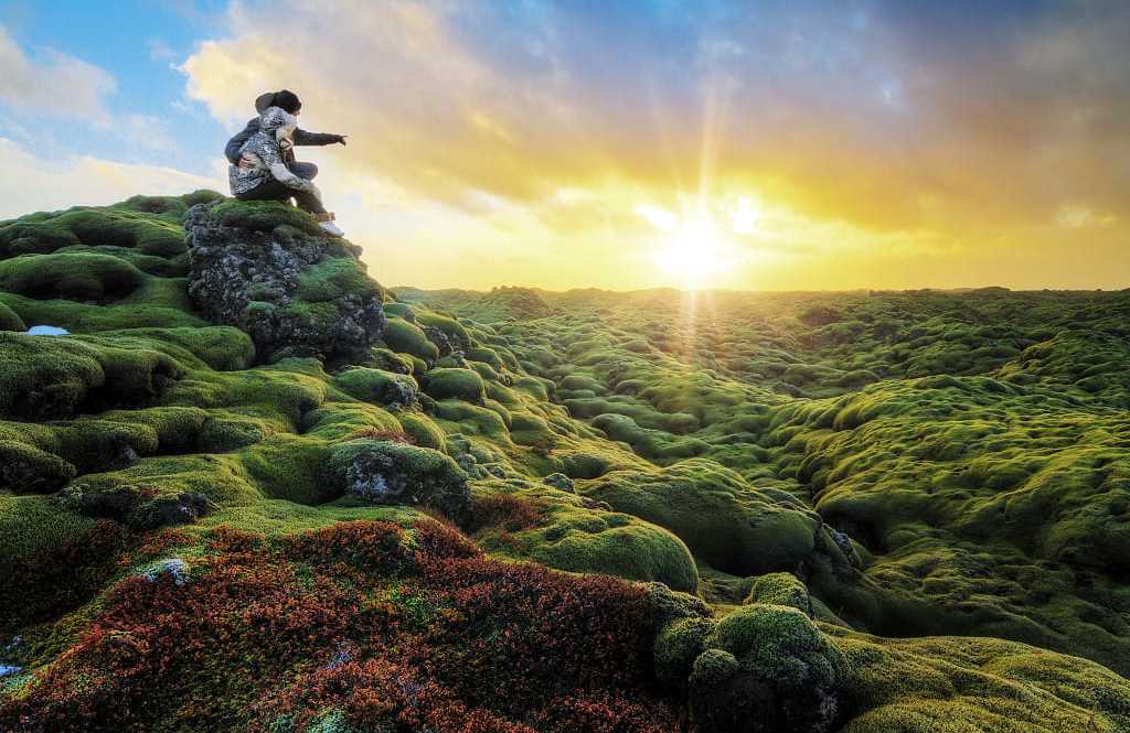 Couple watching the sunrise over Eldhraun lava field in Southern Iceland