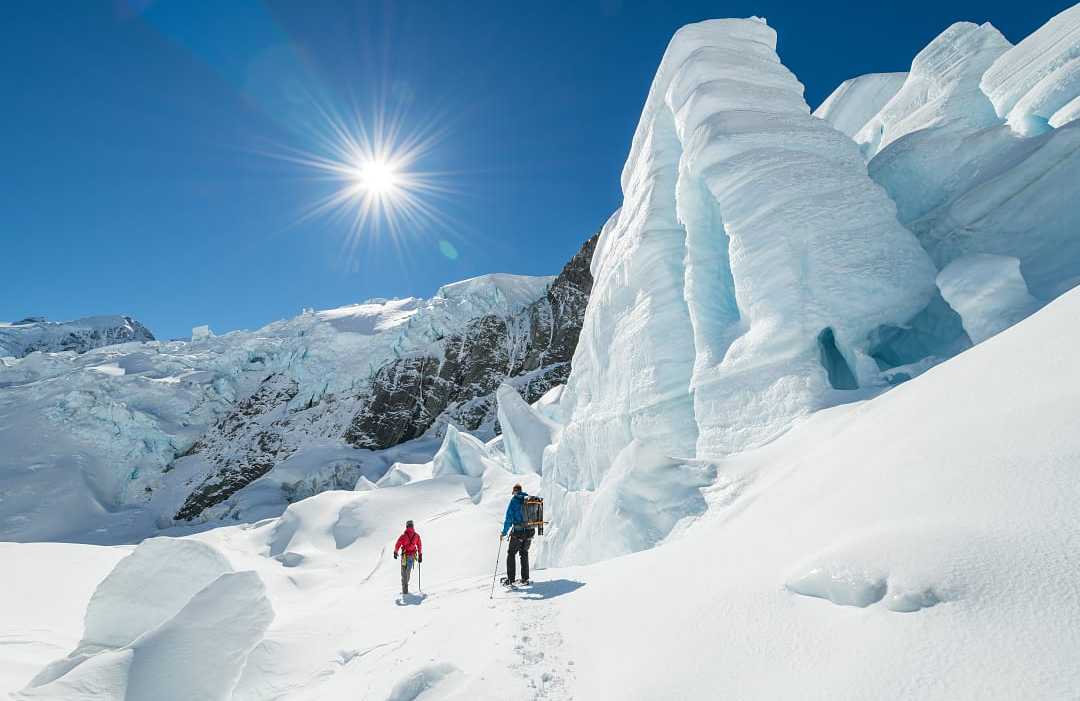 Two people hiking Tasman Glacier in Mount Cook National Park, New Zealand