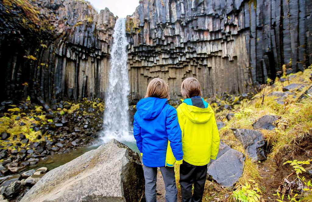 Young siblings at Svartifoss waterfall in Iceland