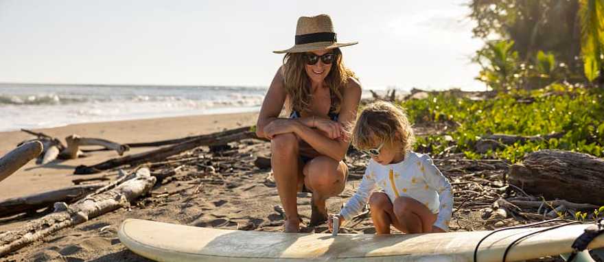 A young girl learning how to wax a surf board from her mother in Costa Rica