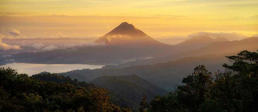 Sunrise view of Arenal Volcano with clouds over Lake Arenal in Costa Rica