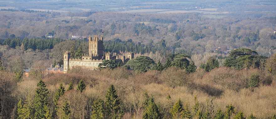 Highclere Castle surrounded by woodland, seen from a distant viewpoint.