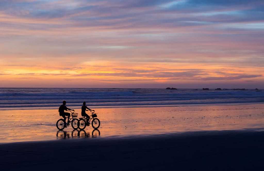 Couple biking on the beach at sunset in Costa Rica