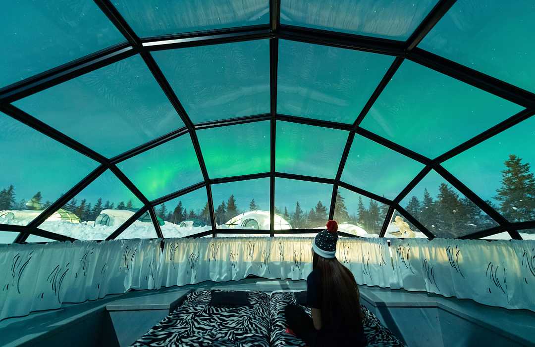 Northern Lights in Lapland, Finland Teen girl watching the Northern Lights from glass igloo in Lapland, Finland