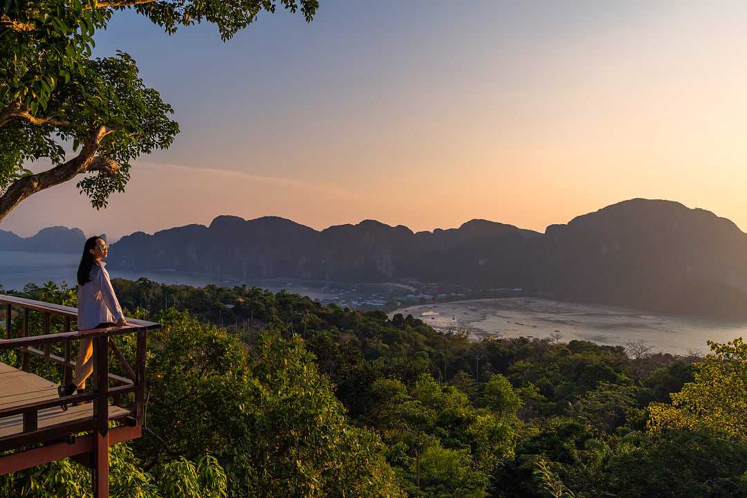 A woman standing at Phi Phi View Point watching the sunset