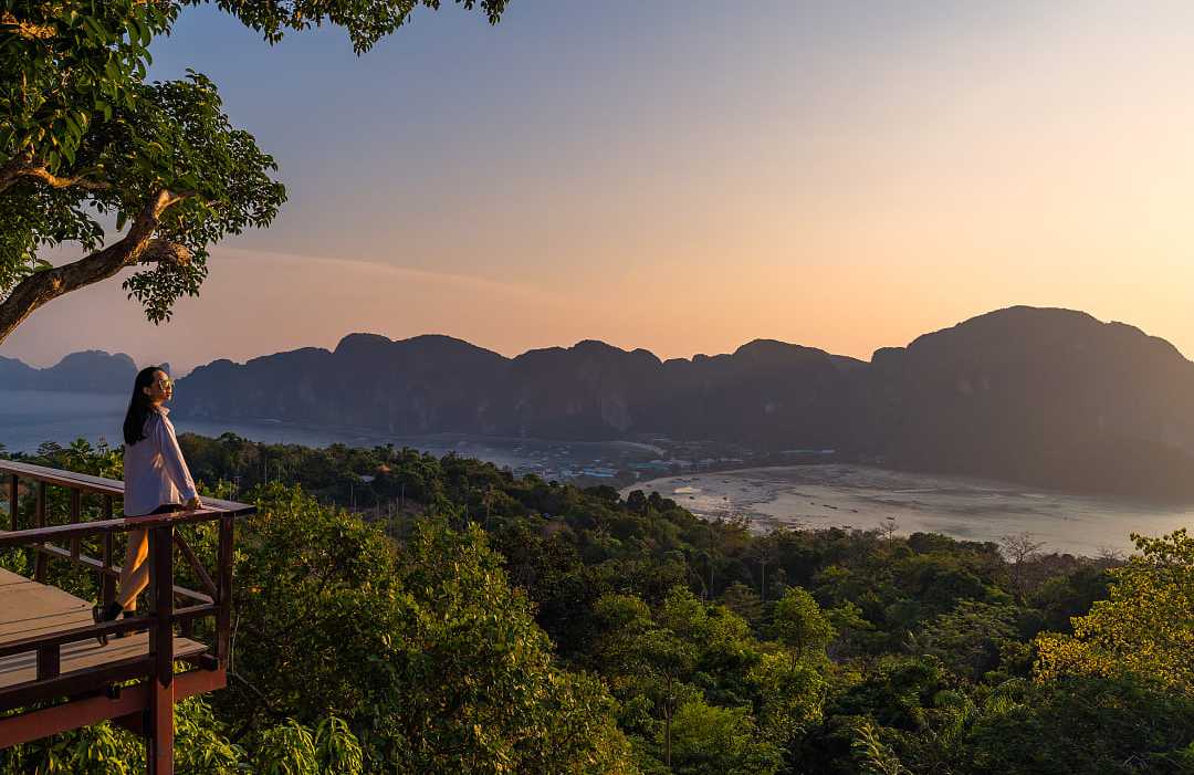 A woman standing at Phi Phi View Point watching the sunset