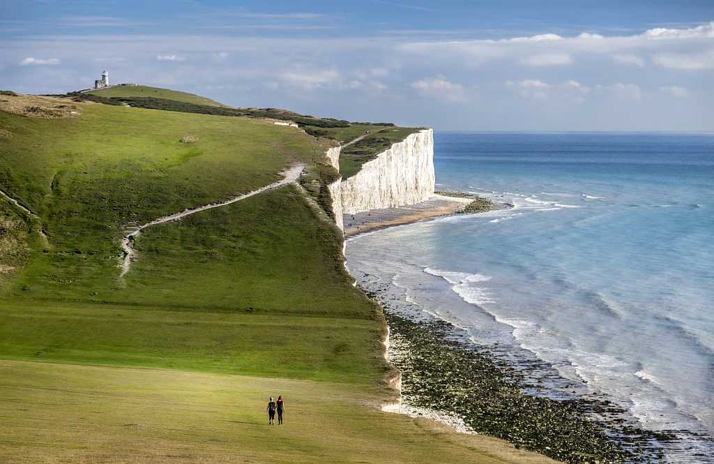 Seven Sisters Chalk Cliffs on the South Coast of England Couple walking on the Seven Sisters Chalk Cliffs on the South Coast of England