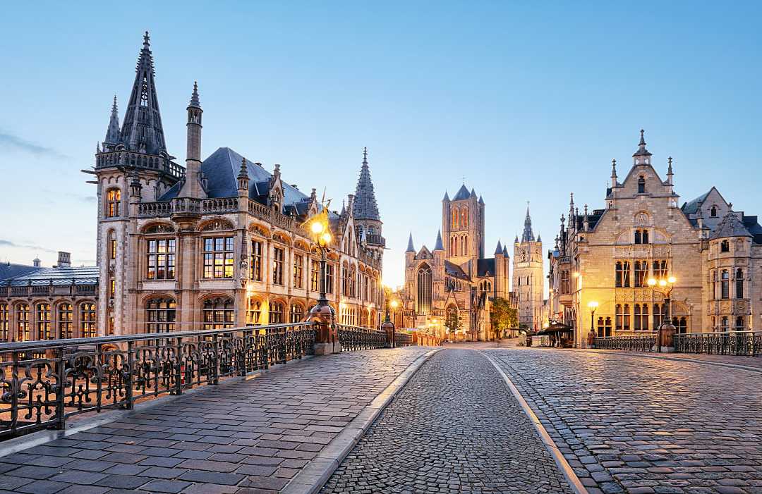 Historic stone buildings and bridge illuminated during a blue hour.