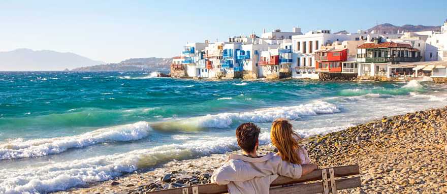 Mykonos, Greece Romantic couple sitting on a beach bench near Little Venice in Mykonos, Greece