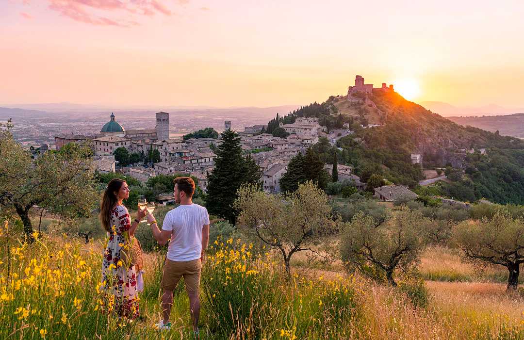 Couple Toasting Wineglasses at sunset in Assisi, Italy