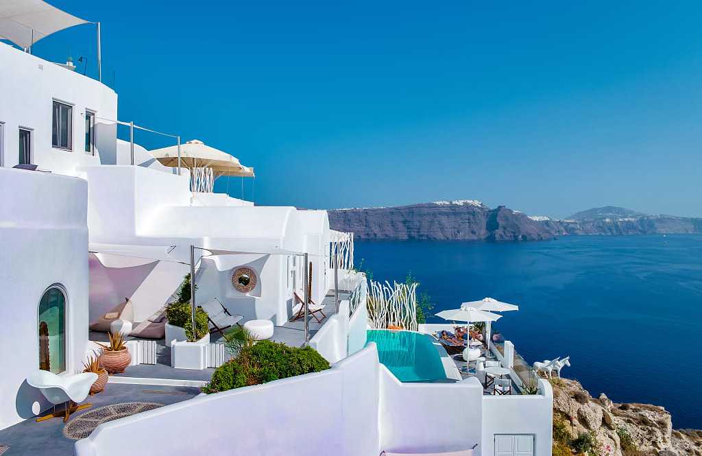 Santorini, Greece Couple lounging poolside at boutique luxury hotel in Santorini, Greece