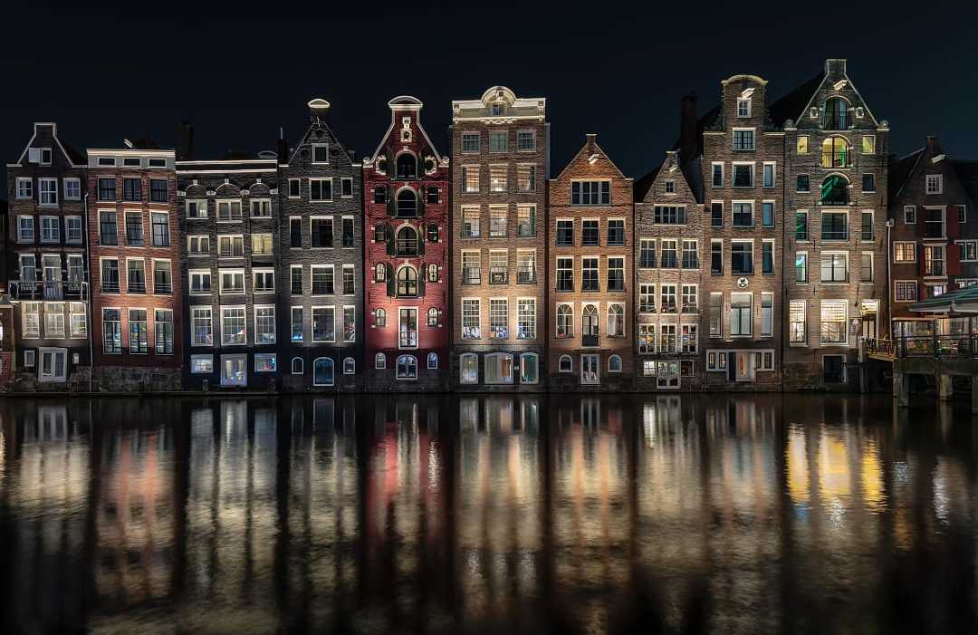 Canal View in Amsterdam, Netherlands Illuminated traditional Dutch gabled houses reflecting in an Amsterdam canal at night.