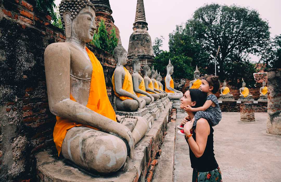 Mother and daughter looking at statues of Buddha in Ayutthaya, Thailand