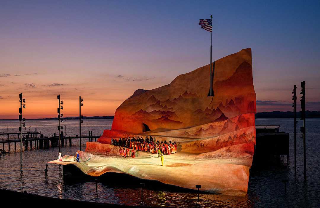 Bregenz Festival 2022 - Madame Butterfly by Giacomo Puccini.  Photo courtesty of Vorarlberg Tourismus / Michael Kemter Open-air opera performance on a floating stage at sunset with a dramatic backdrop and calm waters