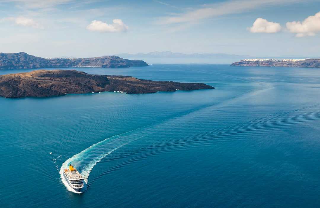 White ferry boat cruising through deep blue water near islands.