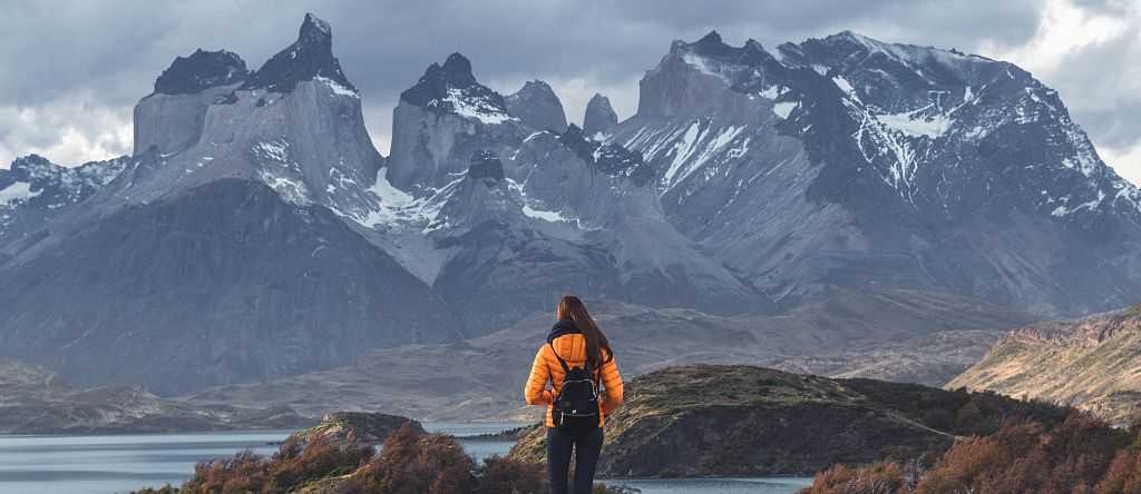 Hiker walking toward Torres del Paine peaks in Patagonia, Chile.