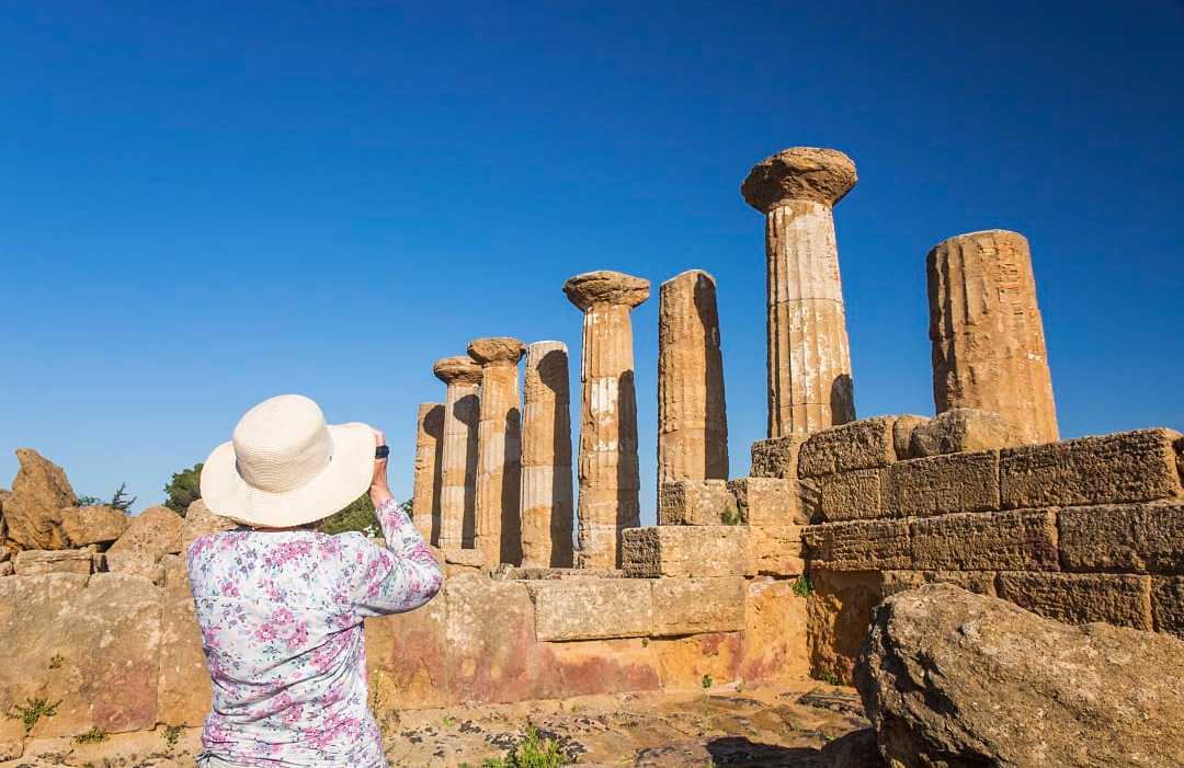 Senior woman taking a photograph at the Valley of the Temples in Sicily, Italy