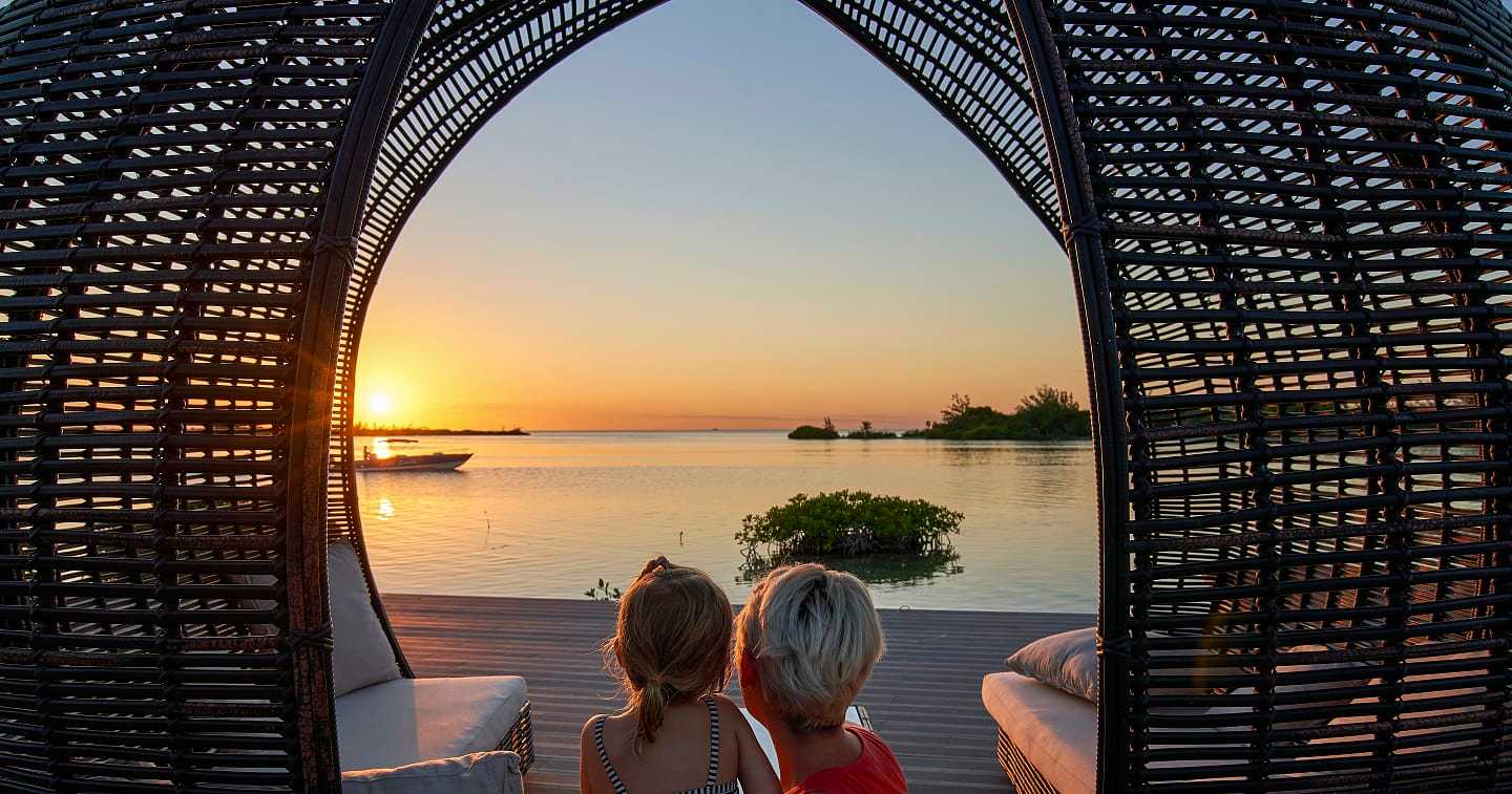 Mother and daughter seen from behind watching a sunset