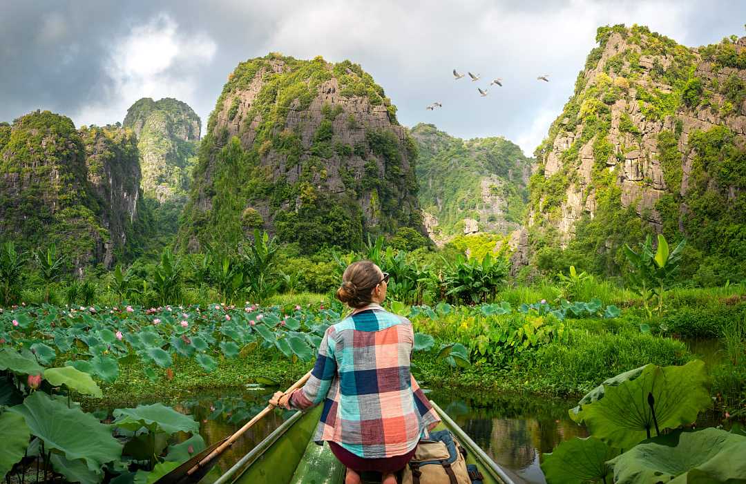 Ninh Binh Province, Vietnam woman travels along river in boat, enjoying picturesque karst mountains in Ninh Binh Province, Vietnam