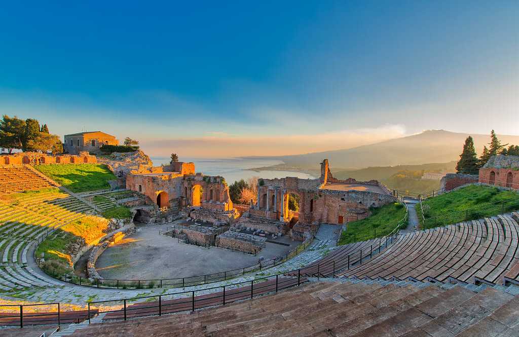 Ancient theatre of Taormina in Sicily with Mount Etna in the background at sunset