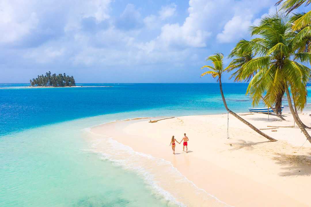 Couple walking hand-in-hand along the beach on San Blas island, Panama