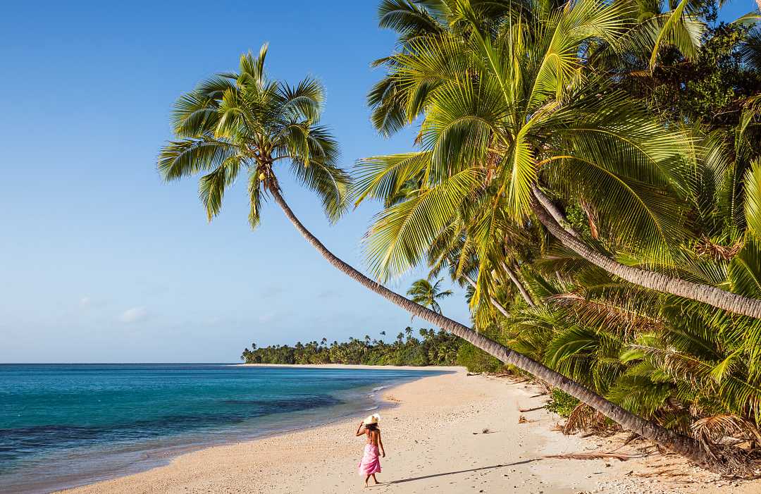 Woman walking the long stretch of beach on Kadavu Isand, Fiji