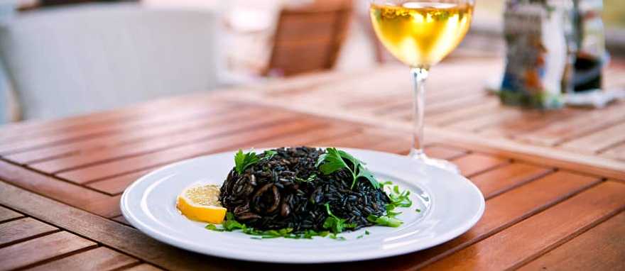Black risotto with seafood and glass of white wine Black risotto with seafood and glass of white wine