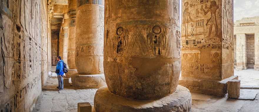 Traveler viewing hieroglyphs on the walls of the Temple of Medinet Habu in Egypt